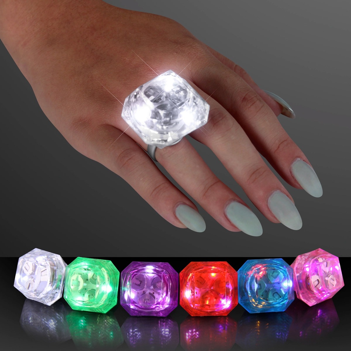 A hand with light blue nails wears a Huge Gem Lighted Ring glowing white, while five more rings in green, pink, purple, red, and blue colors shine on a dark surface.