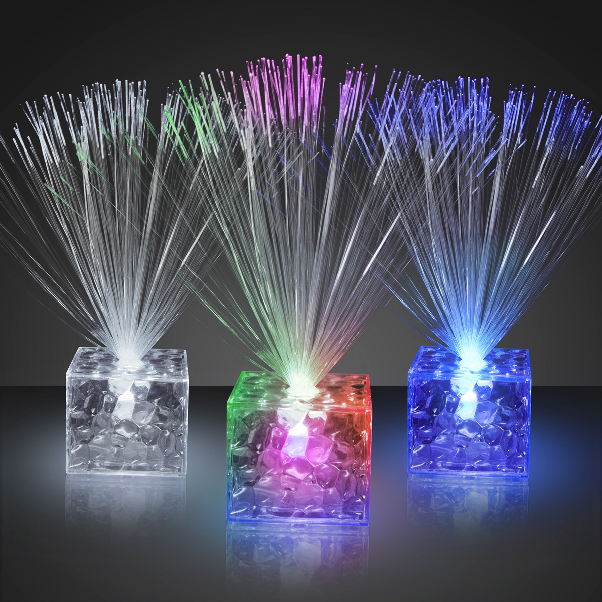 Three 5.5" Light Up Mini Centerpieces feature illuminated fiber optic decorations in clear cube bases, each glowing green, red, or blue and emitting vibrant light strands upward against a dark background.