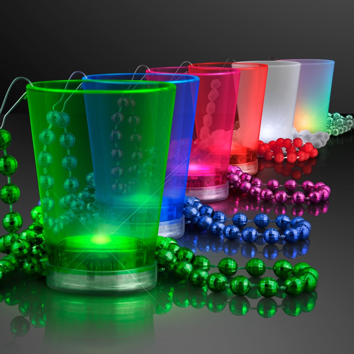Five 1.5 oz. Light up Shot Glasses on Bead Necklaces in green, blue, red, pink, and white are arranged in a row on a reflective black surface, each glowing from below to highlight their vibrant colors.