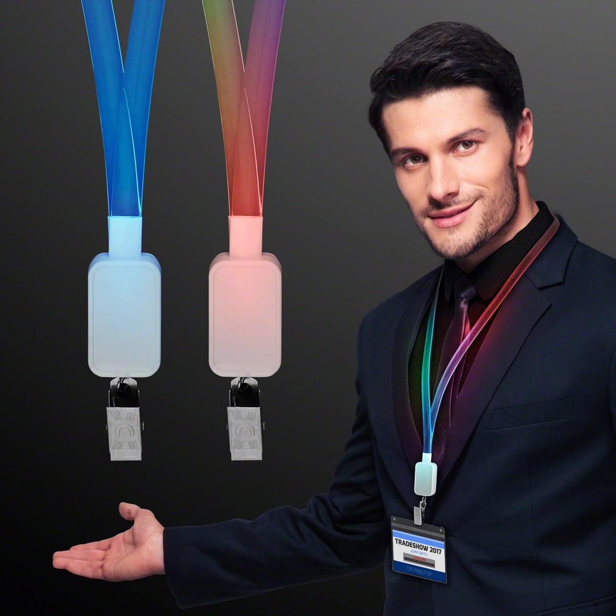 A man in a suit wears a Supernova Light Lanyards LED Badge Holder and gestures toward two glowing Supernova Light Lanyards with USB connectors, displayed beside him against a dark background.